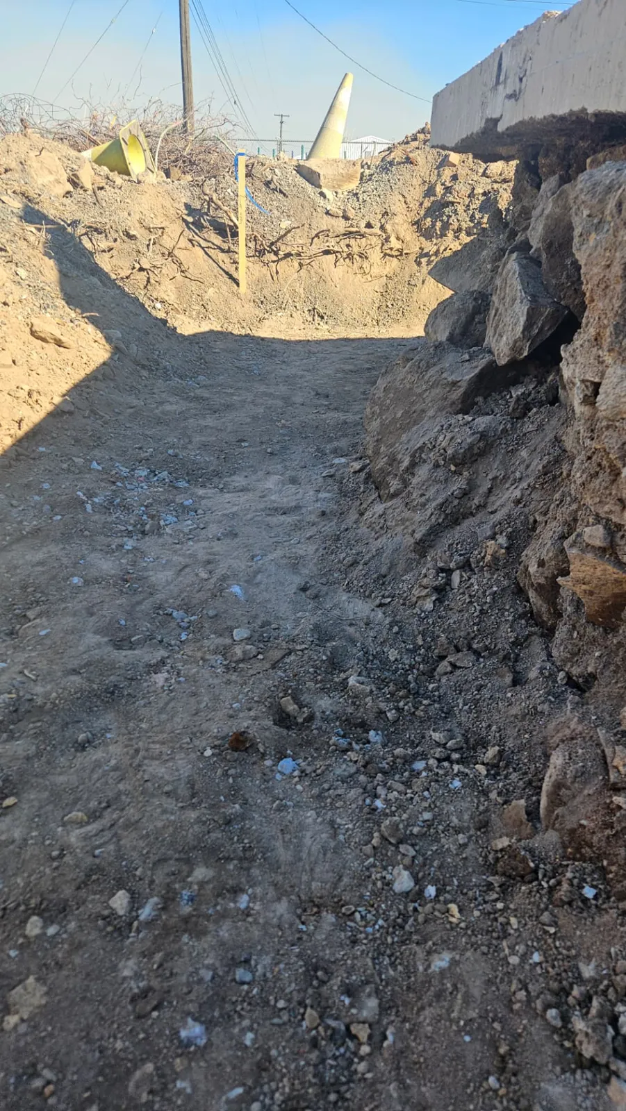 Compacted trench floor next to the old stone base and cut concrete slab