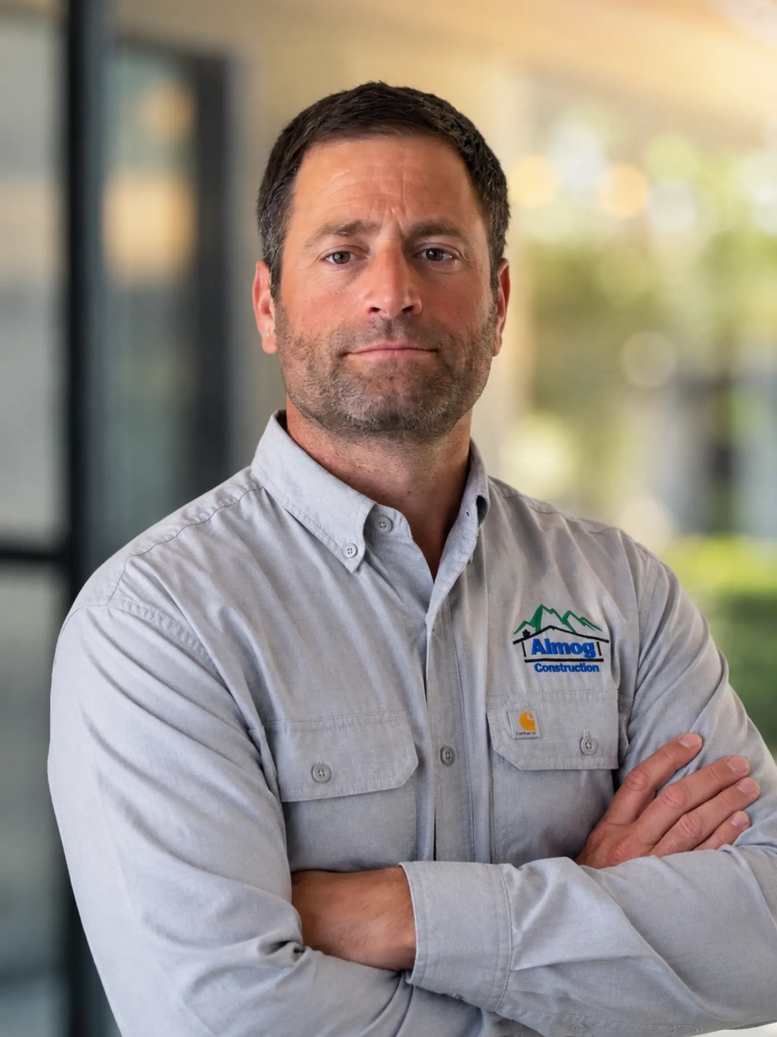 Hagai Almog, owner and founder of Almog Construction, in a gray company shirt with arms crossed