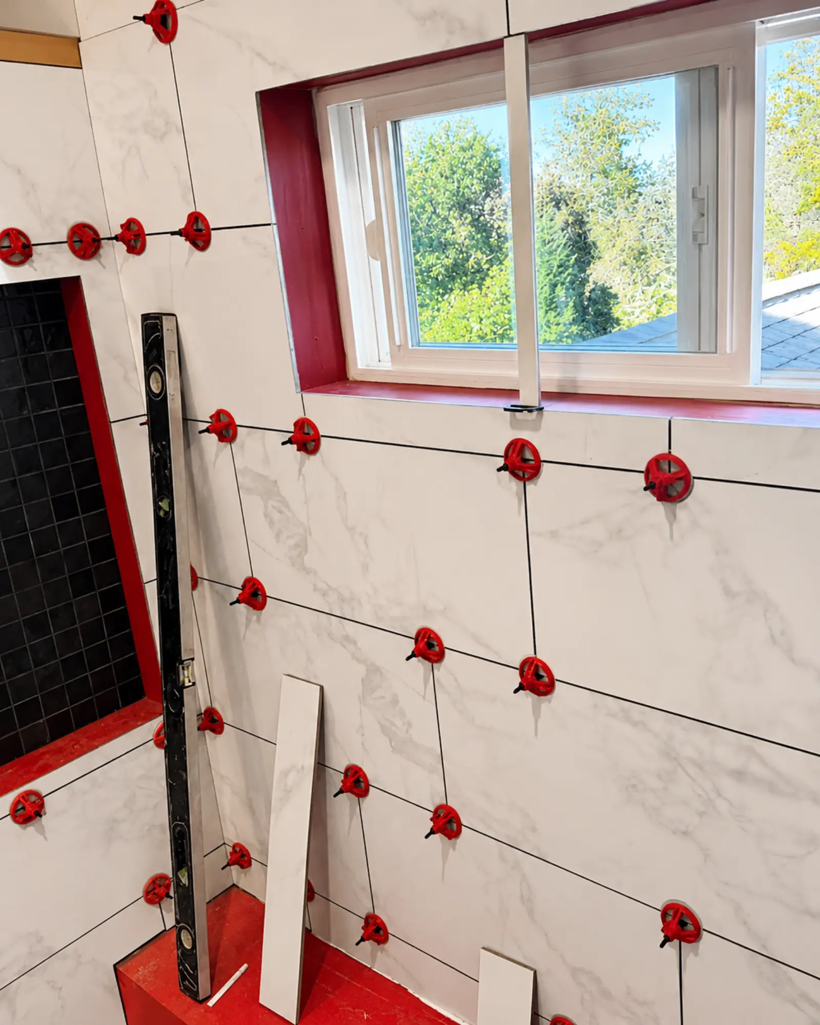 Craftsman tiling a marble bathroom wall for Almog Construction.