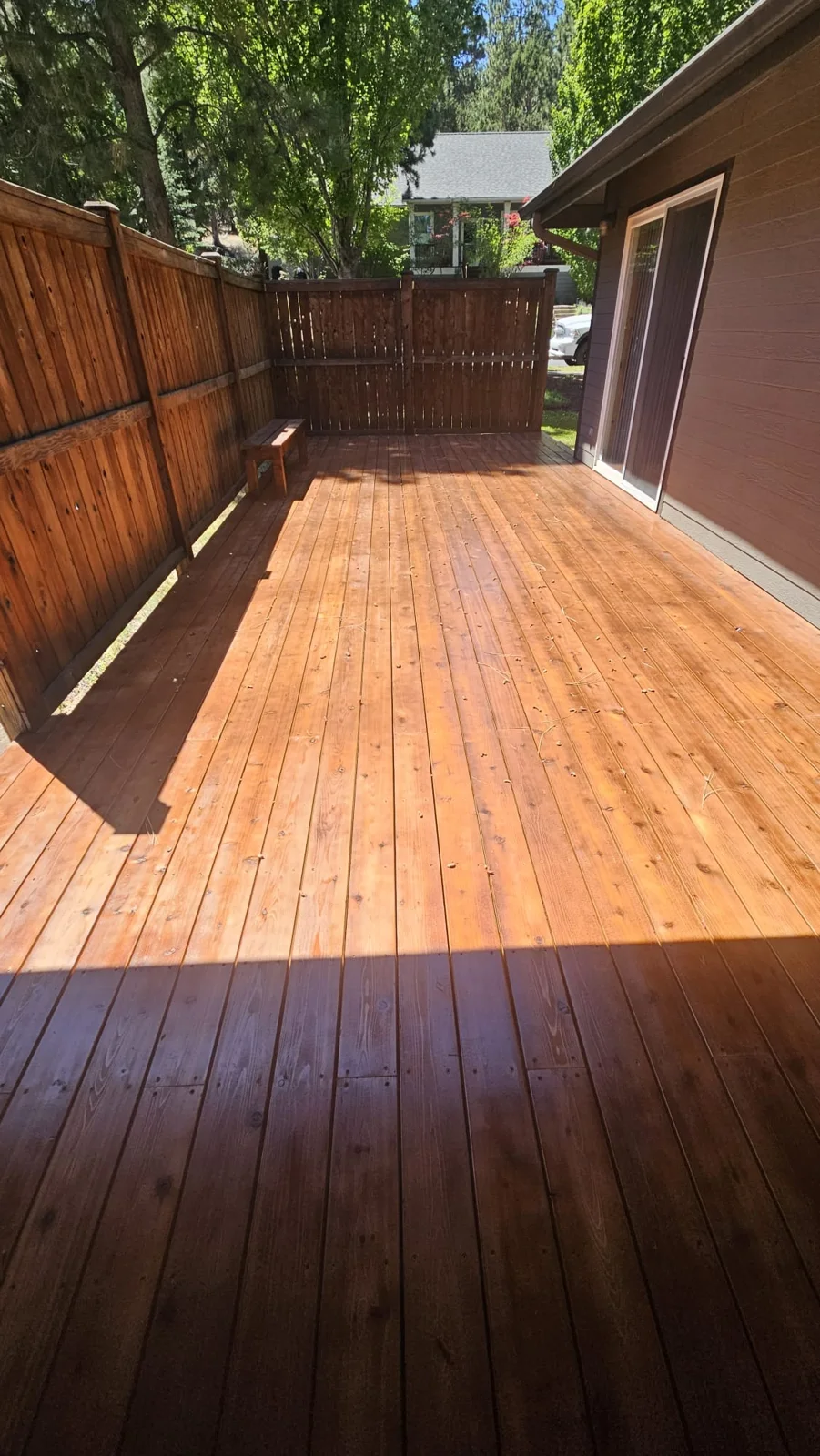 Stained back deck and wood fence with a bench beside a sliding door in Bend, Oregon