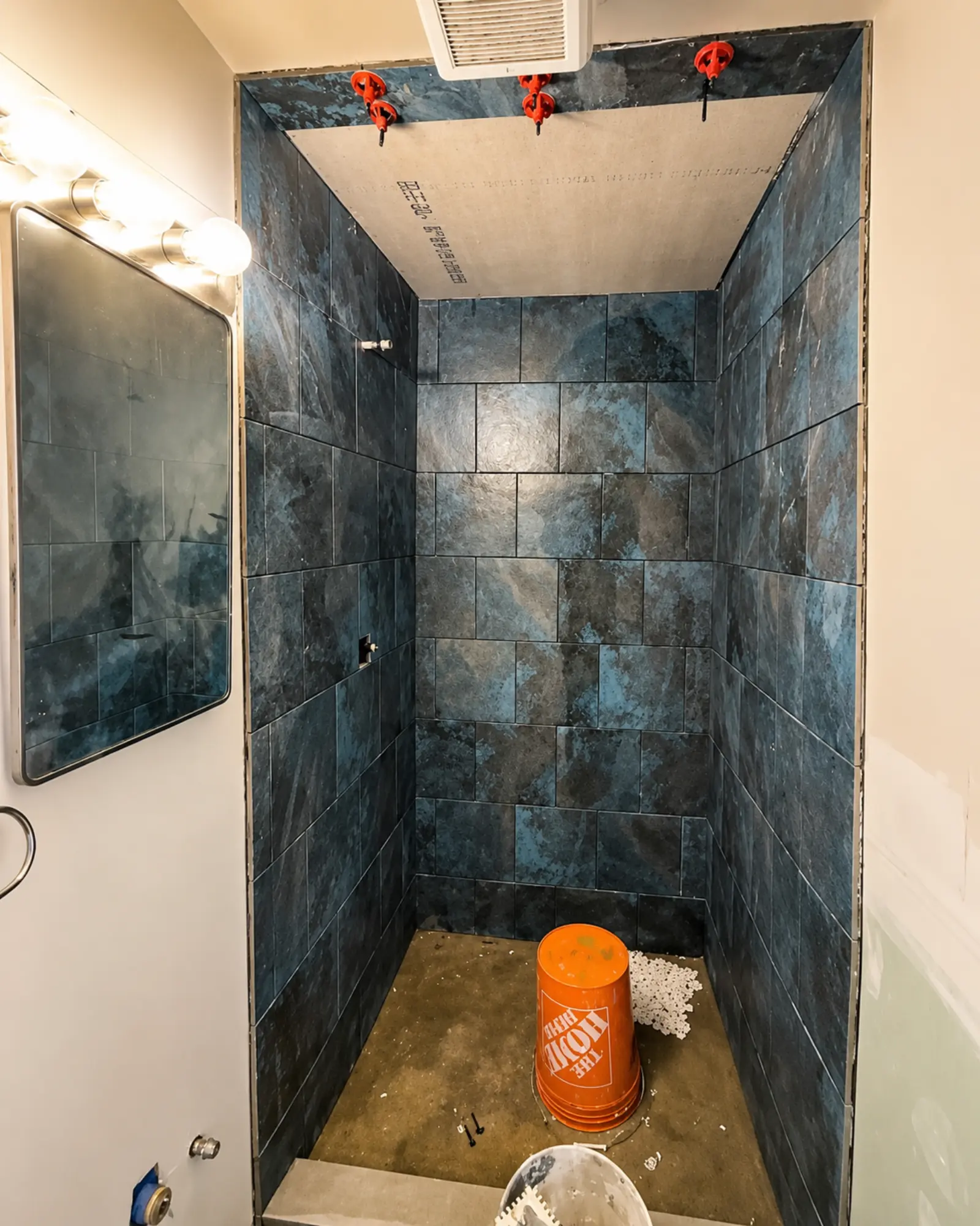 Custom dark-tile shower installation in progress by Almog Construction.